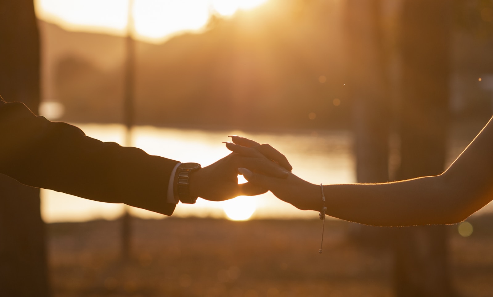 Manos de una pareja unidas al atardecer